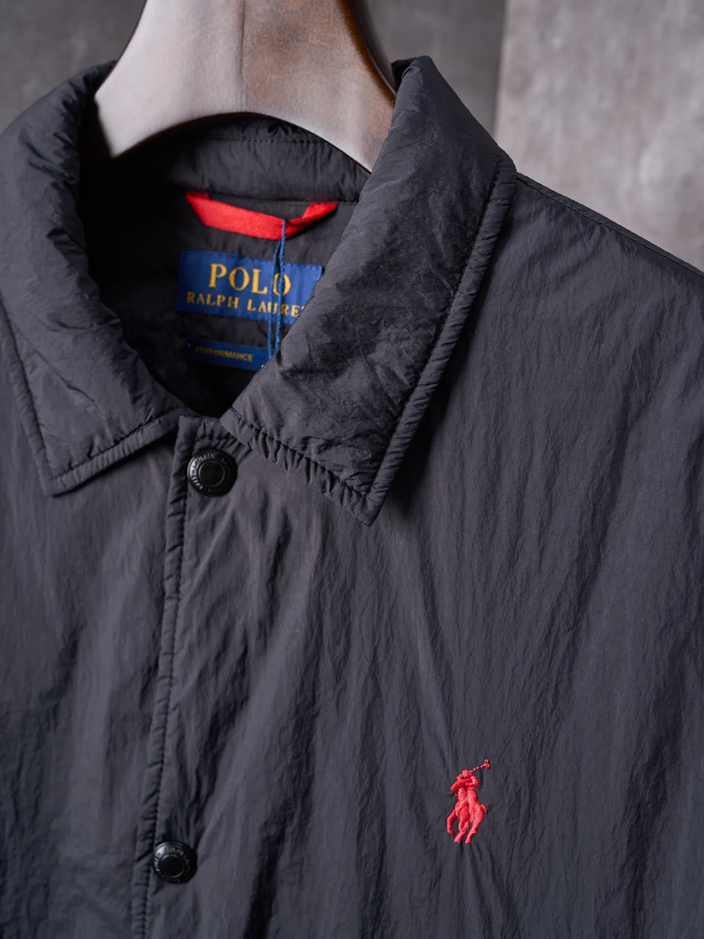 P640 Actual auction] Ralph Lauren/Ralph Lauren Pony Red Label lightweight cotton lapel coach jacket [Ready stock] S M L XL Material: high-density nylon taffeta Features: Density is about 210T-300T, smooth and slightly matte surface, excellent windproof and waterproof performance (with DWR water-repellent treatment), strong wrinkle resistance and easy care, in line with the positioning of American casual "durable and practical".  Color: Classic dark black, using vat dyeing process (dye penetrates into the fiber), the color fastness reaches ISO level 4 or above to avoid fading or color transfer after washing.  2. Lining fabric Material: Lightweight cotton-polyester blended lining (65% Polyester + 35% Cotton) Function: Reduce friction between the fabric and inner clothing, improve wearing smoothness; blended material has both breathability and durability to avoid the stuffy feeling of pure nylon lining.  Version and cutting process Version: Classic Coach Jacket, loose version, slightly dropped shoulder line (shoulder width is 1-2cm wider than the standard version), length to the hips, and slightly tapered straight sleeves, taking into account both freedom of movement and casual style. Embroidery technology: Polo horse logo on the left chest: flat satin stitch embroidery (satin embroidery), embroidery thread: 100% polyester high color fastness embroidery thread (the color number is consistent with the brand’s standard red color card), stitch density 12-15 stitches/cm, the outline of the horse logo is clear, and the details of the rider and horse are burr-free.  Embroidery positioning: precise positioning through the template (12cm from the neckline and 8cm from the placket) to ensure left and right symmetry and centering.  Topstitching technology: The seams of the body are made of double-needle flat seams (needle pitch 3cm/10 needles), the stitches are smooth and straight, the stitching color is dark black (the same color as the fabric), and the stitch width is 0.5cm, which enhances firmness while forming simple decorative lines.  1. Main body splicing, splicing of the front placket and body: The placket is made of double-layer folding + flat seam splicing, with a thickness of about 0.3cm to ensure that the buttons are not easily deformed when fixed; the edges of the placket are cut with a hot knife to avoid burrs.  Sleeve panels are spliced ​​to the body: the armholes are spliced ​​with round-head keyhole machine seams + flat seams. After splicing, the armholes have a natural curvature and no sense of tightness during movement; the height of the sleeves is about 8-10cm, which is in line with the loose characteristics of casual jackets.  Main button: black urea resin button, matte surface treatment, buttonholes are hand-made keyholes (6 strands of cotton thread, keyhole density 8 stitches/mm), the edges of the eyelets are smooth and without burrs.  Collar buttons: The first button on the collar is a hidden button (diameter 12mm), which prevents the collar from opening and improves the neatness of wearing.